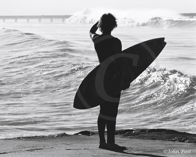 Silhouette of surfer looking at waves in distance