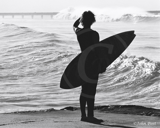 Silhouette of surfer looking at waves in distance